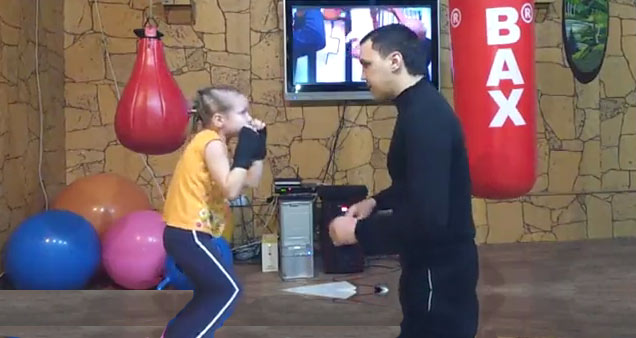 girl and adult trainer boxing in a gym