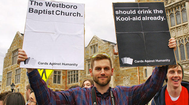 man holding cards against humanity signs