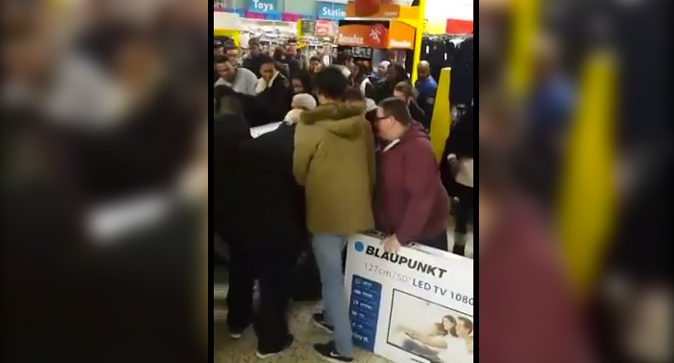 A crowded section of walmart full of people fighting over merchandise.