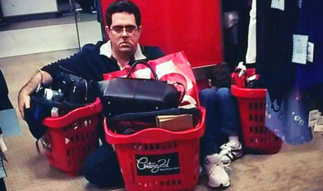 grumpy man sitting on floor among shopping bags