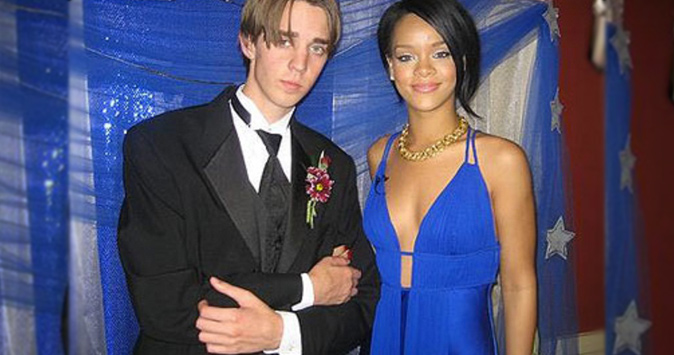 Rihanna in a low-cut blue dress and standing next to her skinny date with hair parted down the middle.