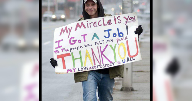 Homeless man happily holds a sign that says: My Miracle is you. I got a job! Thank you. My love and respect to u all.