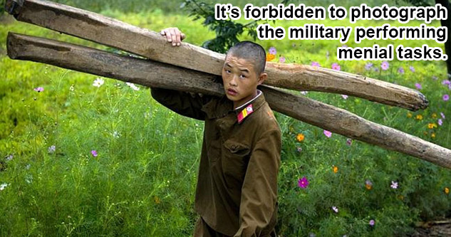 Picured: A young North Korean soldier carrying two logs. Text: It's forbidden to photograph the military performing menial tasks.