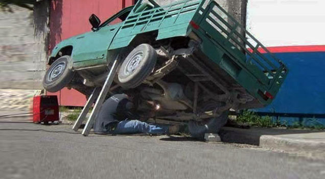 guy working under truck jacked up with boards