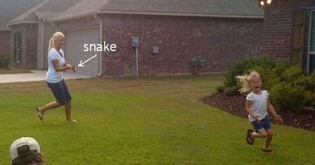 Mom chases frightened daughter in front yard with a snake.