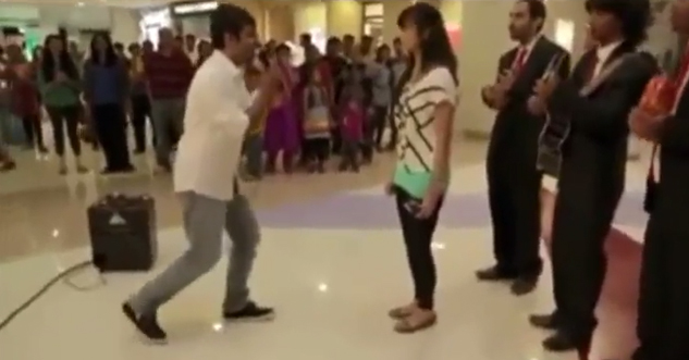 Man in a crowded mall is about to propose to his girlfriend.