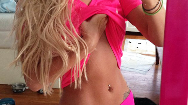 fit tan girl with pink top shows abs and poop in the backround