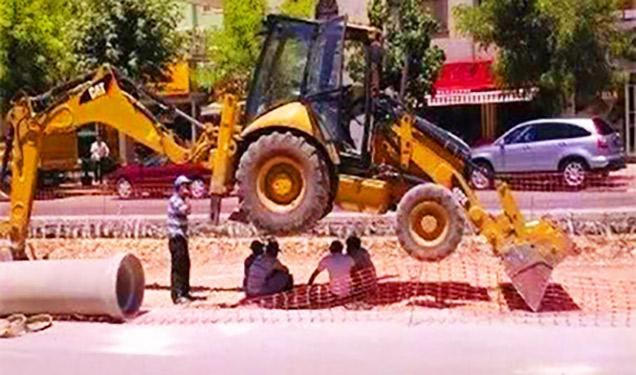 workers sitting under a tractor