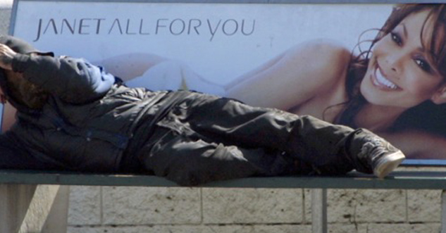 Homeless man sleeps on a bench called 'Janet all for you' with a pic of Janet Jackson.