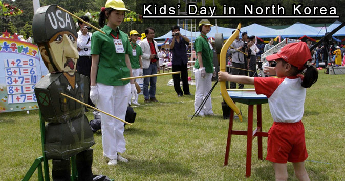 A kid at a festival shooting an arrow at an effigy of a USA soldier.