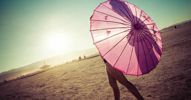 Woman in the desert covers her breasts with an umbrella, but you can see the silhouette of her nipple through the umbrella.