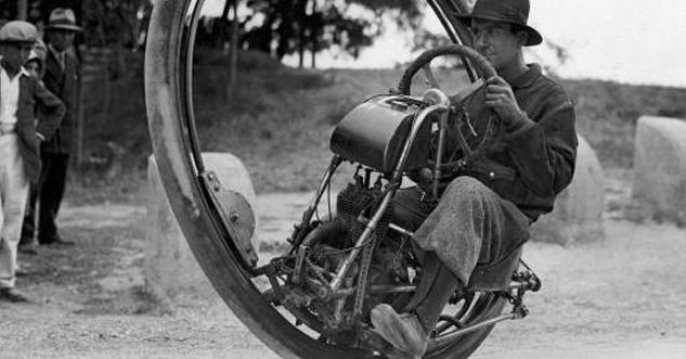 Guy rides a one-wheeled bike.