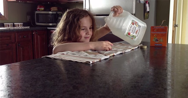 little girl pouring vinegar into baking soda volcano