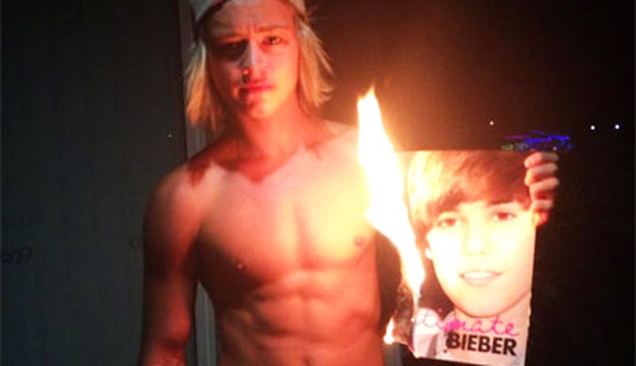 guy with his shirt off and a burning picture of Justin Bieber