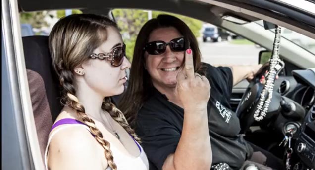 woman flips off camera daughter looks embarrased