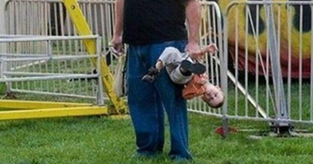 dad carries son in one hand, by his son's arm and leg.