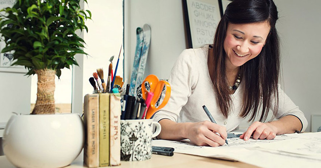 Woman laughs while drawing on a piece of paper.