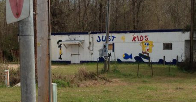A derelict mobile home has children's cartoons painted on the side and the text: Just 4 Kids
