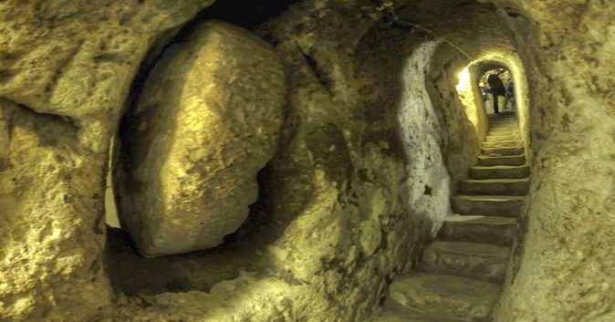 man looks down a cave with a stairway carved into it.