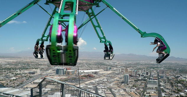 a weird, scary ride swings in a circle far above a city-scape.