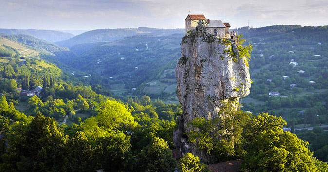 houses on a narrow rock formation sticking up hundreds of feet from the surrounding land.