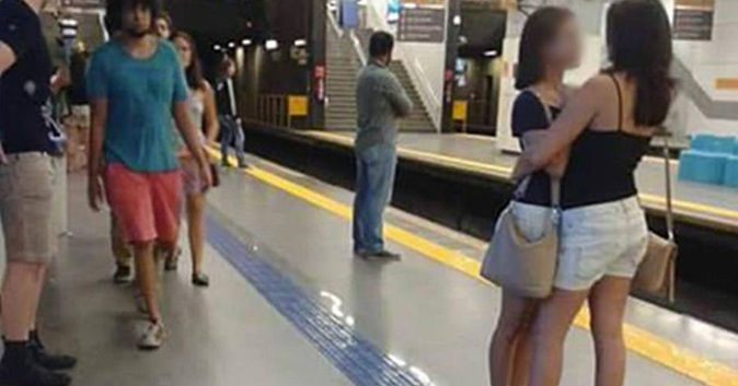 Girls hug each other romantically at a subway station.