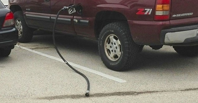 ripped gas pump hanging from a car