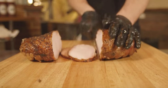 gloved hands slicing a chunk of meat