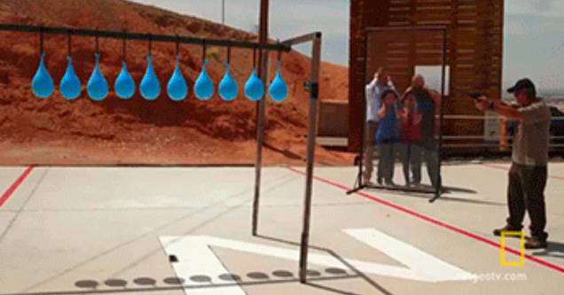 row of balloons tied from a rope and person aiming gun at them