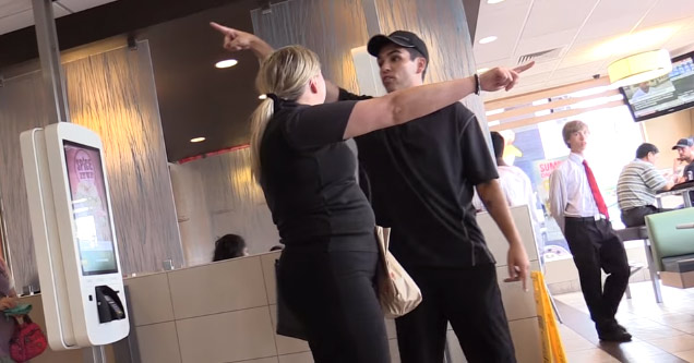 woman and a McDonald's employee standing in front of each other pointing in different directions