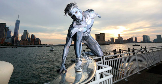 person in silver bodysuit on a surfboard