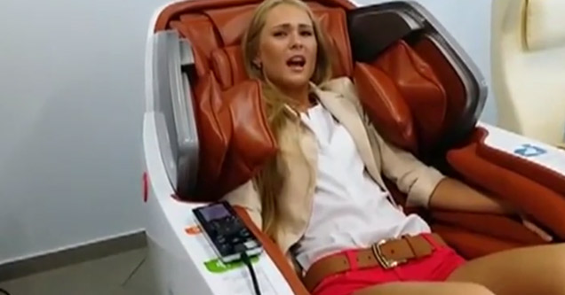 blonde woman with a distressed expression sitting in a red massage chair