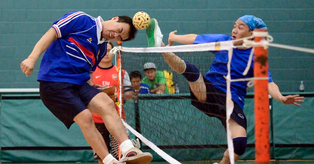 player kicking tiny ball over a net and hitting another player's head