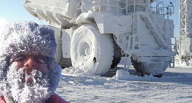 man with frozen beard next to vehicle covered in snow