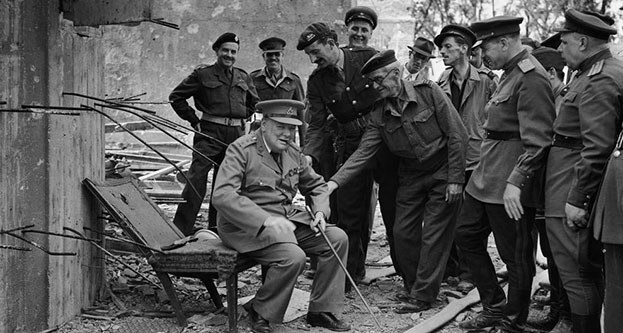 Winston Churchill sitting in the charred remains of Hitler’s armchair, July 1945.