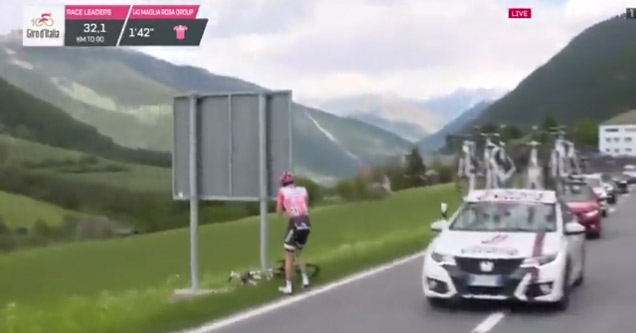 cyclist in pink shirt running off side of the road to poop