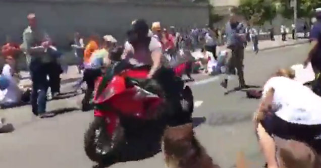 man on red motorcycle rides through crowded street