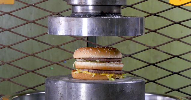 Hydraulic press crushing a Big Mac cheeseburger into a disgusting mess