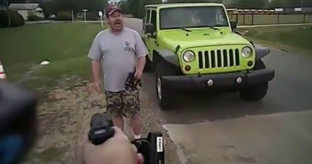 cop holding tazer pointed at man by green jeep