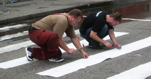 two men laying down crosswalk stripes