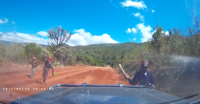 a man with a machete heading toward the hood of a jeep or car