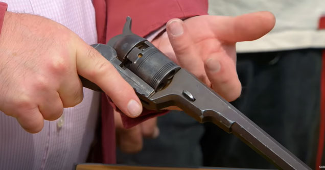 an appraiser holding an old colt revolver