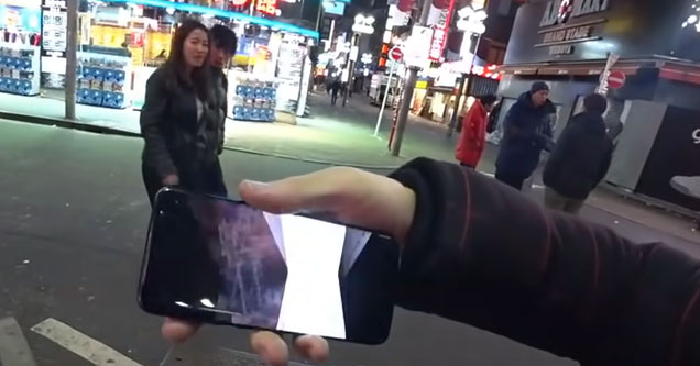 a streamer holding his phone while a couple walks by