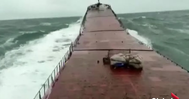 a huge wave crashing into a cargo ship