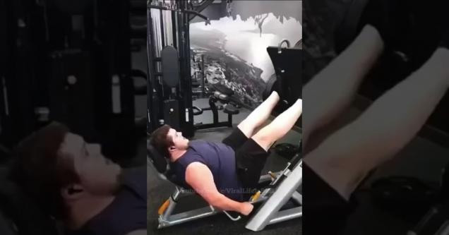 a big guy in blue shirt and black shorts power lifting with his legs