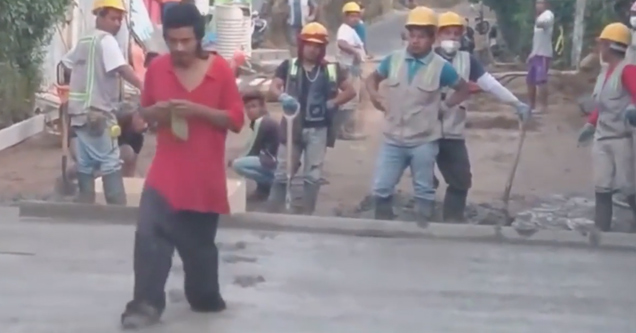 guy walking through wet cement in front of construction workers