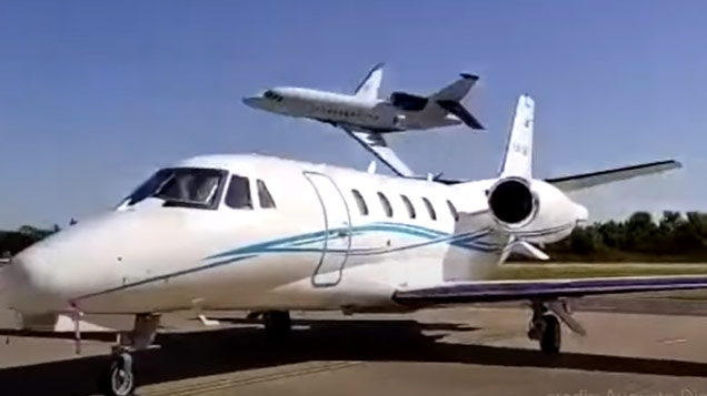 a jet flying very low behind a parked airplane