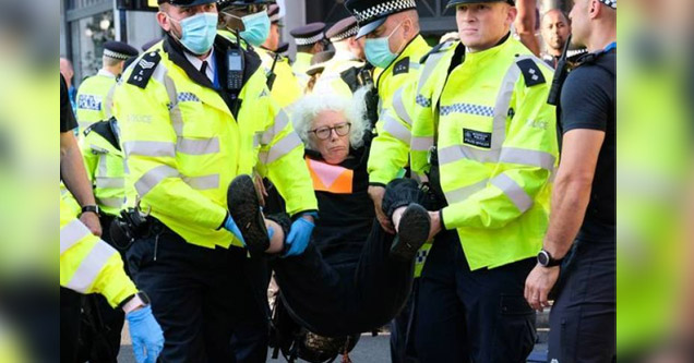 an old woman being carried away by police