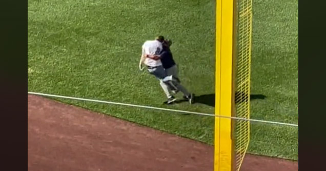 a guy running onto the baseball field gets tackled