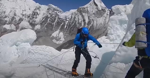 a hiker on everest crossing a crevasse on a ladder